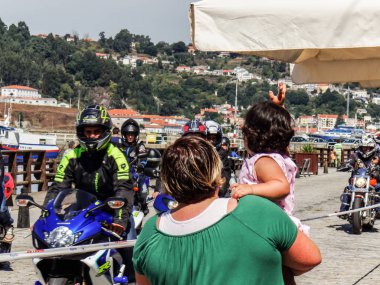 Anne ve kızı bir bisikletçinin konsantrasyonu motosikletler izliyor