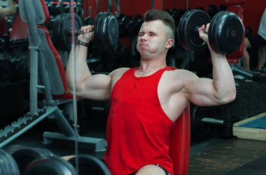 Kırmızı tişörtlü adam spor salonunda olduğunu