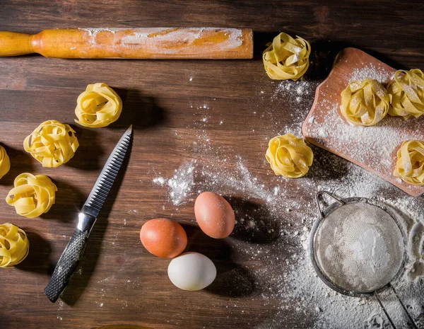 Tagliatelle on a brown wooden background. Cooking Italian pasta. View from above