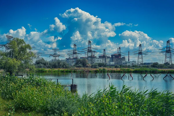 High voltage power lines against a cloudy sky with reflection in a pond. Nature — Stock Photo, Image