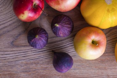 Tahta arka planda sulu mor incirler, elmalar ve kavun. Sonbahar natürmort, üst manzara. Yatay çerçeve