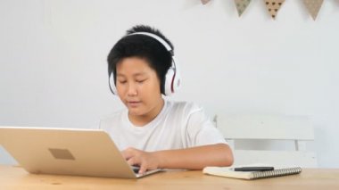 teknoloji, oyun ve insan konsepti - kulaklıklı çocuk evde dizüstü bilgisayarda oyun oynuyor.