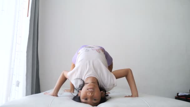 小女孩做体操锻炼和桥梁瑜伽姿势在家庭床上 — 图库视频影像