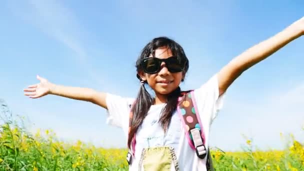 亚洲女孩戴着太阳镜欣赏着黄色的花朵田野 — 图库视频影像