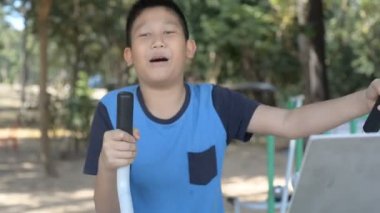 Asyalı çocuk egzersiz donanımları açık park yapıyor.