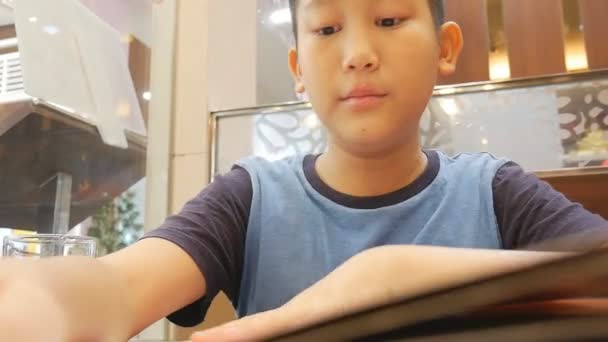 メニュー ブックやポイントを読んでアジアのかわいい男の子 — ストック動画