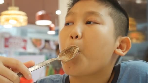 アジアの少年はカフェでアイスクリームを食べています — ストック動画