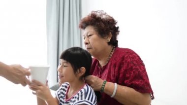 Bir bardak su büyükannesi onu saç örgü ise içerken Asyalı kız.