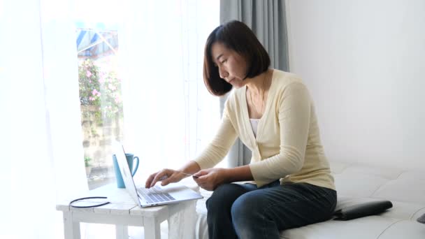 Asian Woman Makes Online Purchase Credit Card Laptop Sitting Sofa — Stock Video