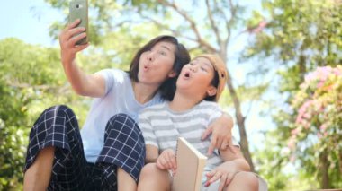 Asya anne ve oğlu parkı açık ve selfie smartphone birlikte, Aile yaşam konsepti ile oturuyor