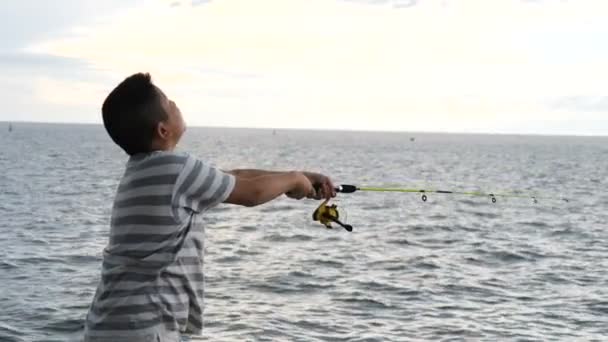 太陽が沈むホアヒン桟橋での男の子釣り — ストック動画