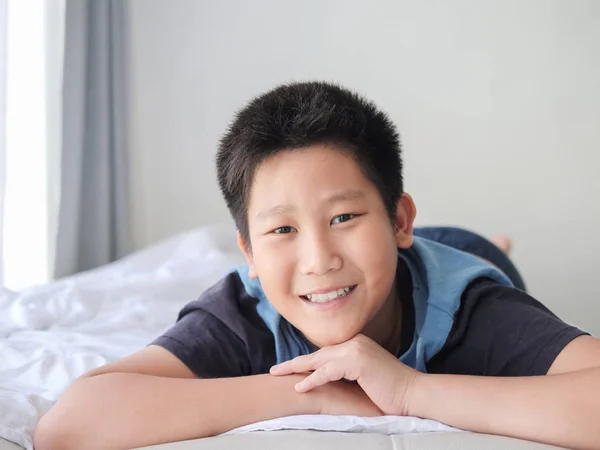 幸せなアジアのプレティーンの少年の自宅のベッドの上に横たわる — ストック写真