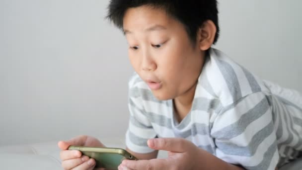 Asiatiska Boy Med Smartphone Som Spelar Spelet Säng — Stockvideo