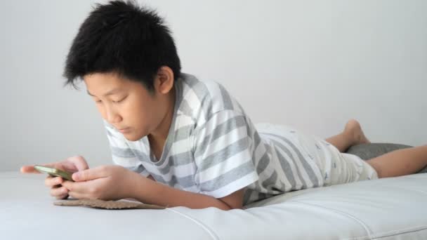 Asiatiska Boy Med Smartphone Som Spelar Spelet Säng — Stockvideo