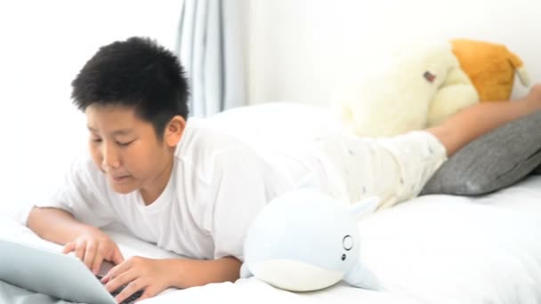 Ευτυχισμένος Ασίας Preteen Αγόρι Ξαπλωμένος Στο Κρεβάτι Και Χρησιμοποιούν Φορητό — Αρχείο Βίντεο