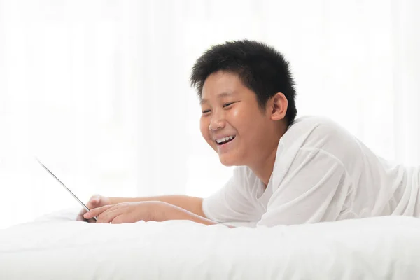 Skrattande Asiatiska Preteen Pojke Som Ligger Sängen Och Använder Laptop — Stockfoto