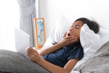 Mutlu Asyalı kız yatakta evde tablet kullanma .