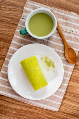 Ahşap masa üzerinde sıcak içecek matcha yeşil çay pasta.