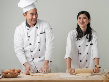 Asya şefler pizza veya masada ekmek hamur hazırlama gülüyor, yaşam tarzı kavram çalışması.