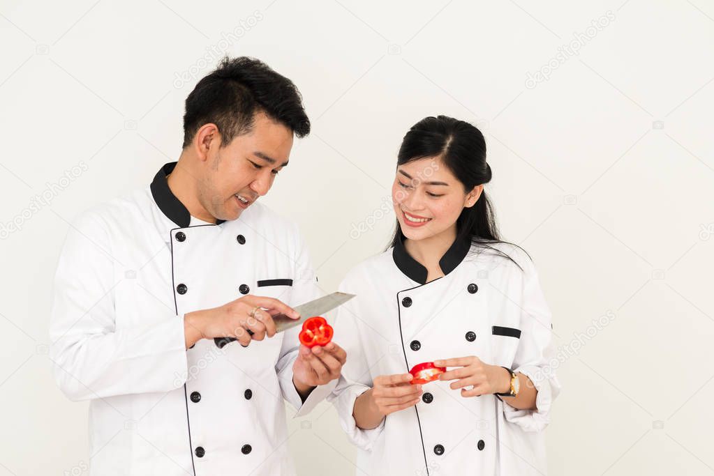 Asian chef man teaching his cook helper for slicing red chili pepper, work lifestyle concept.