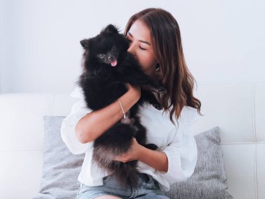 Yaşam tarzı kavramı siyah köpeğini evde, Divan oynamaktan mutlu Asyalı kadın