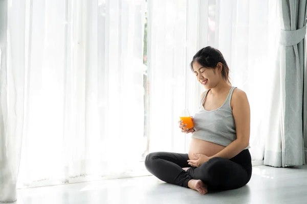 Mulher Grávida Asiática Segurando Copo Suco Laranja Sentado Perto Janela — Fotografia de Stock