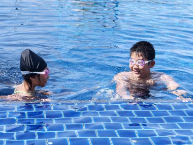 Mutlu çocuklar güneşli gün havuzda yüzer öğrenme.