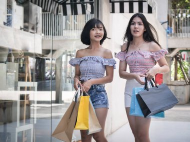 Yürüyüş ve alışveriş torbaları tutan mutlu Asyalı Genç kızların yaşam tarzı kavramı.