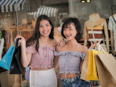 Dükkanın önünde, yaşam kavramı alışveriş torbaları gösterilen mutlu Asyalı Genç kız.