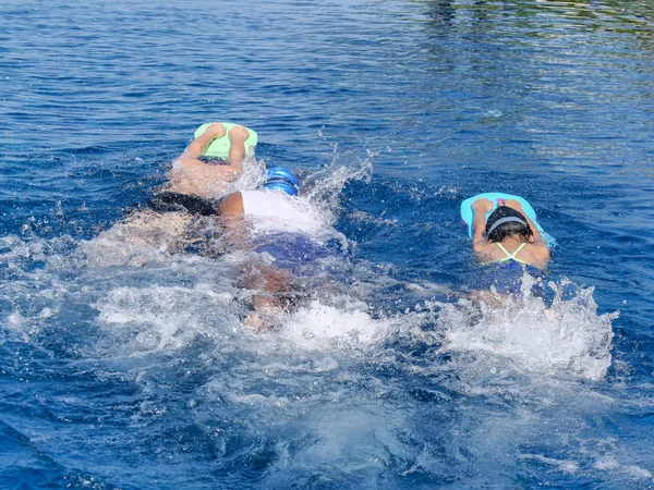 Los niños aprenden a nadar en el tablero de espuma con su entrenador en —  Fotos de Stock