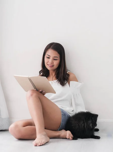 Счастливая Азиатская Женщина Читает Книгу Сидит Дома Полу Своей Черной — стоковое фото