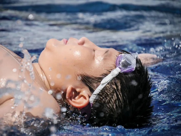 快乐的亚洲学龄前男孩躺在游泳池上后 完成游泳在阳光明媚的日子 — 图库照片