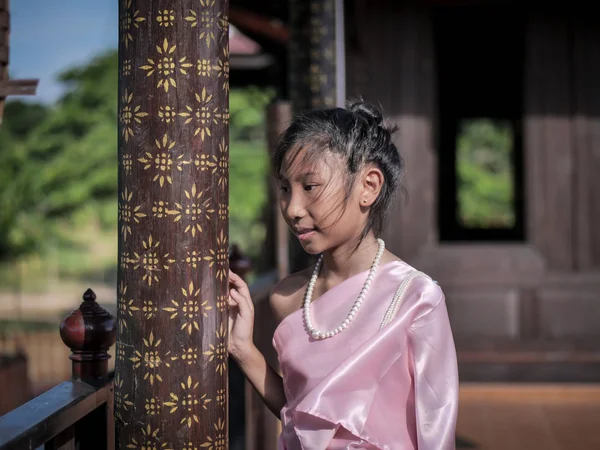 微笑的亚洲女孩穿着泰国服装与古老的老式木制房子的背景 — 图库照片