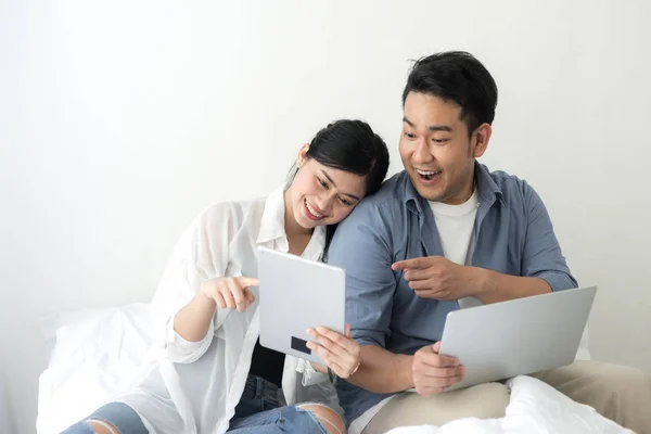 Happy Asian couple using laptop at home, lifestyle concept.