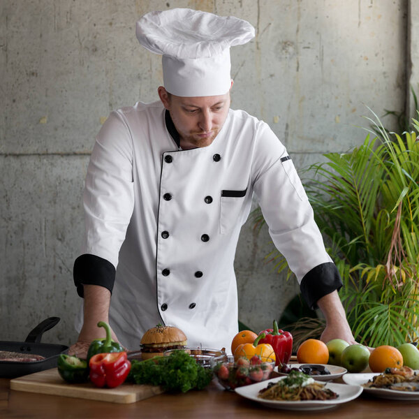 Professional chef looking at food and vegetable on table.