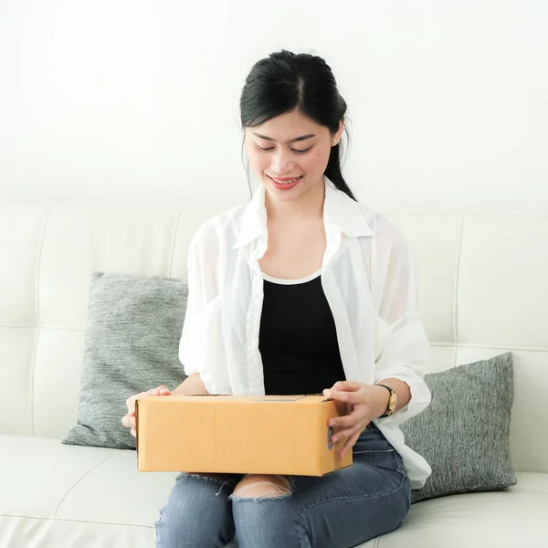 delivery, mail and people concept - smiling Asian woman opening cardboard box at home.