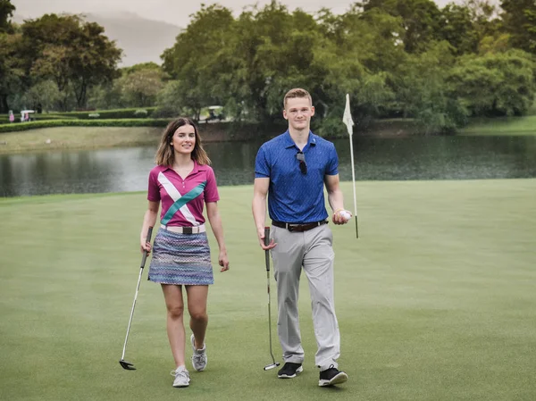 愉快的高尔夫球手夫妇走在绿色的领域 — 图库照片