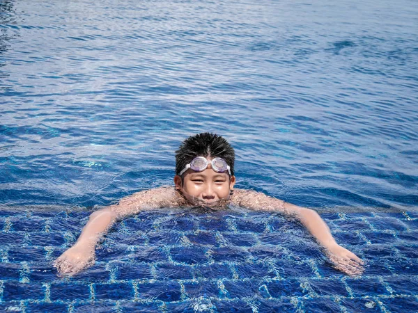 阳光明媚的日子里 亚洲男孩戴着护目镜 在游泳池里游泳 — 图库照片