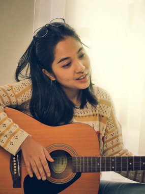 Asyalı kadın yaşam tarzı kavramı iskambil gitar ve şarkı bir şarkı evde,.