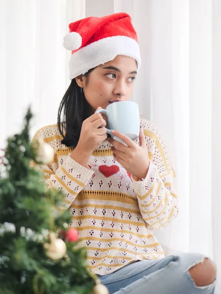Asiatin Mit Weihnachtsmütze Und Kaffeetasse Und Blick Aus Dem Fenster — Stockfoto