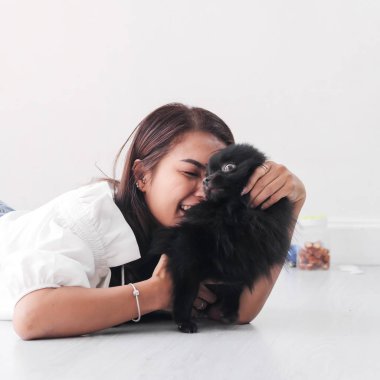 Yerde yatarken ve siyah köpeğini pencere ışık, yaşam tarzı konsepti ile dokunmadan mutlu Asyalı kadın.