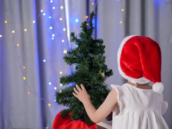 サンタの帽子を自宅のクリスマス ツリーを飾ると幸せなアジアの女の子 — ストック写真