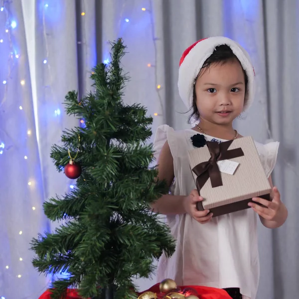 サンタの帽子を自宅のクリスマス ツリーを飾ると幸せなアジアの女の子 — ストック写真