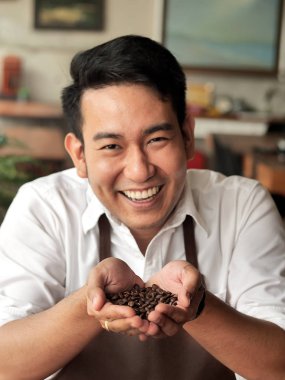 Kahve çekirdekleri onun elinde tutan mutlu Asya barista adam.