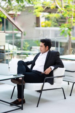 Şehir geçmişi olan kafede oturan düşünceli Asya iş adamı.