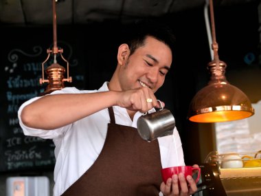 Latte sanat için kırmızı kahve fincanı içine süt dökme mutlu Asya barista.