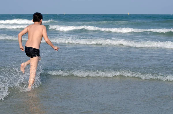 Asyalı çocuk denize güneşli bir günde çalıştıran.