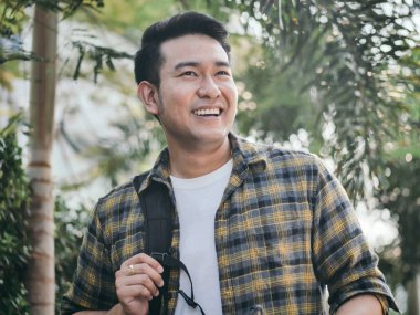 Sırt çantası ve palmiye ağaç arka plan ile mutlu Asya turizm.