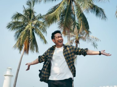 Mutlu duygu ve Hindistan cevizi ağacı arka plan, yaşam tarzı concep.t elleriyle yükselterek sırt çantası ile Asya adam