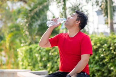 Parkta açık bir şişe su içme Asain spor adamı.